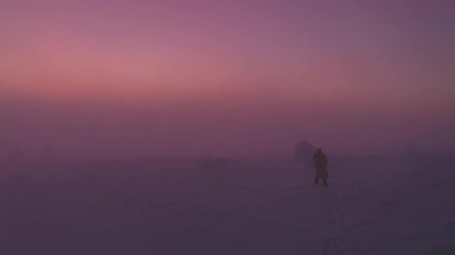 Aerial drone view of a Person walking on a mountain, foggy sunset, in Lapland