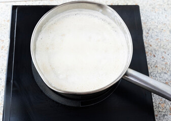 Cooking chocolate oatmeal porridge in a saucepan on a cooker