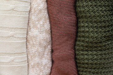 Stack of folded sweaters in neutral colors. Top view.