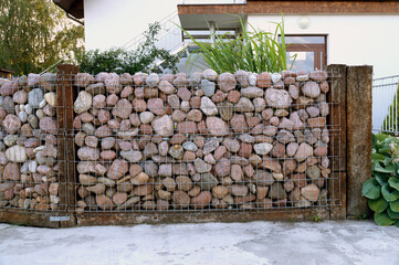 Self-made fence made of stones. A specific form of a gabion made of pebble stones.
