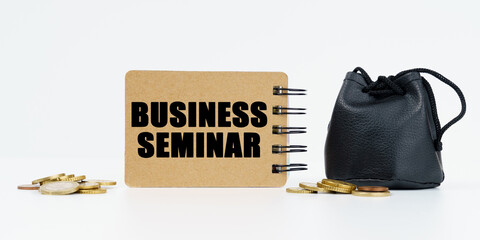 On a white background lies a bag with money, coins and a notebook with the inscription - BUSINESS SEMINAR