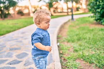 Cute and sad little boy crying having a tantrum at the park on a sunny day. Beautiful blonde hair male toddler frustrated with tears on face outdoors