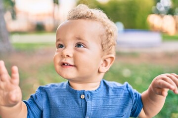 Cute and happy little boy having fun at the park on a sunny day. Beautiful blonde hair male toddler playing outdoors
