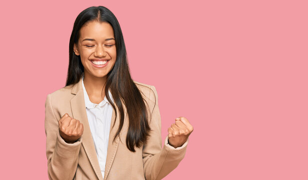 Beautiful hispanic woman wearing business jacket excited for success with arms raised and eyes closed celebrating victory smiling. winner concept.
