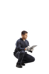 Worker in a uniform kneeling and writing a document