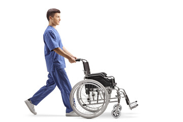 Full length profile shot of a male nurse pushing an empty wheelchair