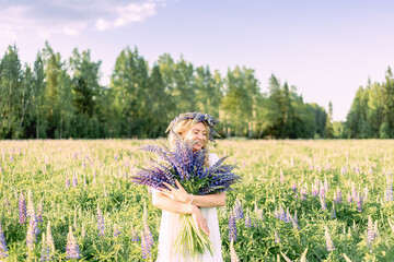 A hippy girl holding bouquet of wildflowers in her hands. Girl hid her face behind bouquet of...