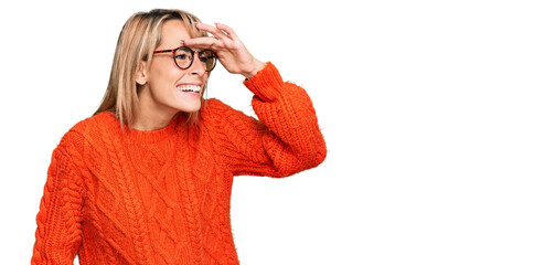 Beautiful blonde woman wearing casual clothes and glasses very happy and smiling looking far away...