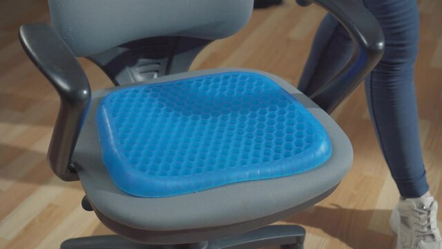Woman office worker puts a seat cushion pillow on an office chair
