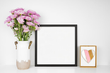 Mock up black frame with vase of purple mum flowers and heart decor. Mother's Day decor theme....