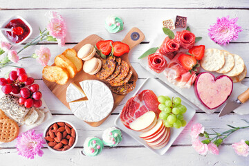 Mother's Day theme charcuterie table scene against a white wood background. Assortment of cheeses,...