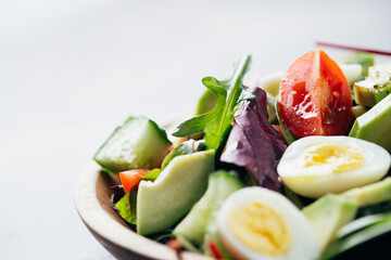 Close up view of salad with tomatoes, avocado, cucumber and eggs.