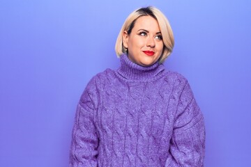 Beautiful blonde plus size woman wearing casual turtleneck sweater over purple background smiling looking to the side and staring away thinking.