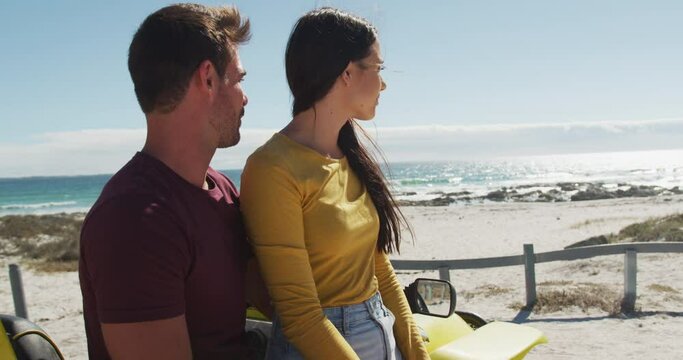 Happy caucasian couple sitting in beach buggy by the sea talking