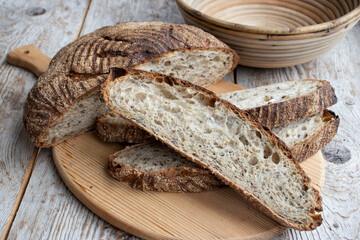 Whole grain bread with sourdough, cut into slices on a wooden board.