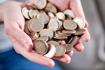 Savings, close up of cupped female hands holding golden coins