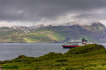 passenger ship sailing through the fjord towards the town of Seydisfjordur, Iceand, during summer season