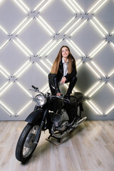 Naklejka na ściany i meble Young fashion girl posing in black leather with motorcycle.