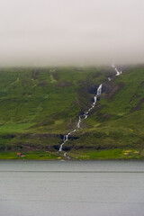 waterfall flowing in the sea on a eastern Icelandic fjord near Seydisfjordur during summer 