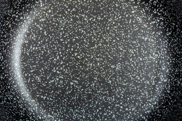 dark surface of a frying pan with a non-stick coating of dark color with dots closeup top view, texture of the coating of kitchen utensils.