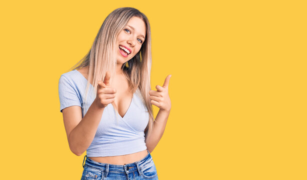 Young beautiful blonde woman wearing casual clothes pointing fingers to camera with happy and funny face. good energy and vibes.