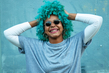 street portrait of black afro american woman smiling with sunglasses and long blue curly hair