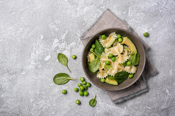 Farfalle pasta with green peas, avocado and spinach leaves