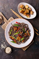 A dish of Asian cuisine. Soba noodles with red bell pepper, green onions and fried tofu cheese