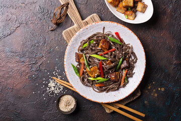 A dish of Asian cuisine. Soba noodles with red bell pepper, green onions and fried tofu cheese