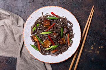 A dish of Asian cuisine. Soba noodles with red bell pepper, green onions and fried tofu cheese