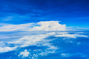 Landscape of fluffy white clouds on a dark blue sky. View from the plane at high altitude