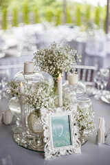 Obraz na płótnie Canvas Close up of wedding table decoration with white wildflowers and candles. Tender decor. Celebrating concept. 