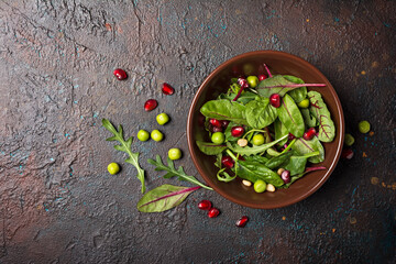 A plate with mix of fresh leaves, pomegranate, green peas and pine nuts for salad