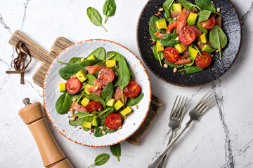 Healthy salad with fresh baby spinach, cherry tomatoes, avocado and salmon fish