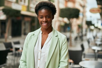 Naklejka premium Young african american businesswoman smiling happy standing at the city