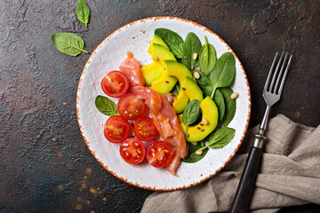 Healthy salad with fresh baby spinach, cherry tomatoes, avocado and salmon fish