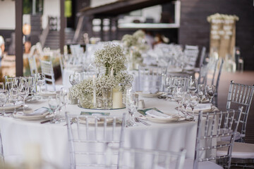 Close up of wedding table decoration with white wildflowers and candles. Tender decor. Celebrating concept.

