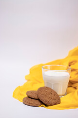 oat cookies with a glass of milk on yellow silk fabric isolated on white background
