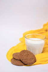 oat cookies with a glass of milk on yellow silk fabric isolated on white background