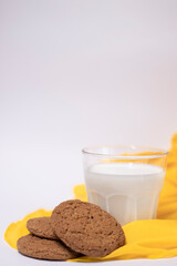 oat cookies with a glass of milk on yellow silk fabric isolated on white background