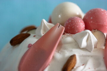 Easter cake decorated with white icing, meringue, pink decorative chocolate balls, nuts. Homemade Easter bread top view on blue background. A recipe for a traditional Easter cake.