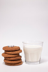 glass of milk near oat cookies with a sign MILK written with white little cubes isolated on white background. healthy breakfast snack