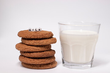 glass of milk near oat cookies with a sign MILK written with white little cubes isolated on white background. healthy breakfast snack