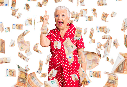 Senior beautiful woman with blue eyes and grey hair wearing a red summer dress pointing finger up with successful idea. exited and happy. number one.