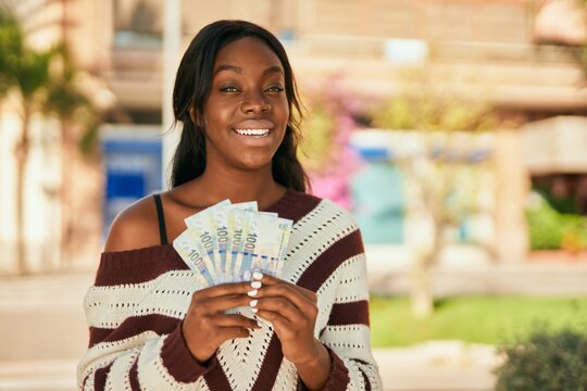 Young african american woman smiling happy holding south africa rands at the park.