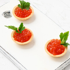 red caviar in a round tartlets on a white table