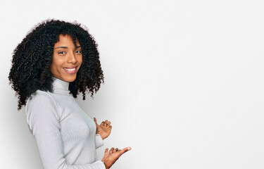 Young african american girl wearing casual clothes inviting to enter smiling natural with open hand