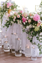 Wedding table decoration of the newlyweds with fresh pink and white flowers and candles.