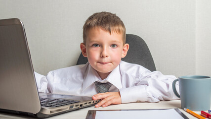 Young business boy is working in the office. A child disguised as a businessman. Funny kids