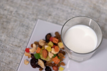 glass of milk near dried fruits, candied fruits, raisins, nuts. healthy breakfast snack